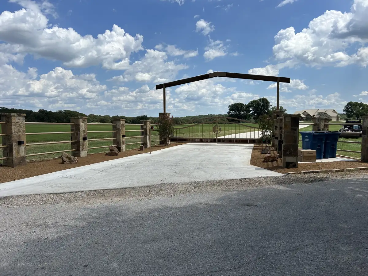 Channel drain at driveway entry with stone gate in Weatherford TX
